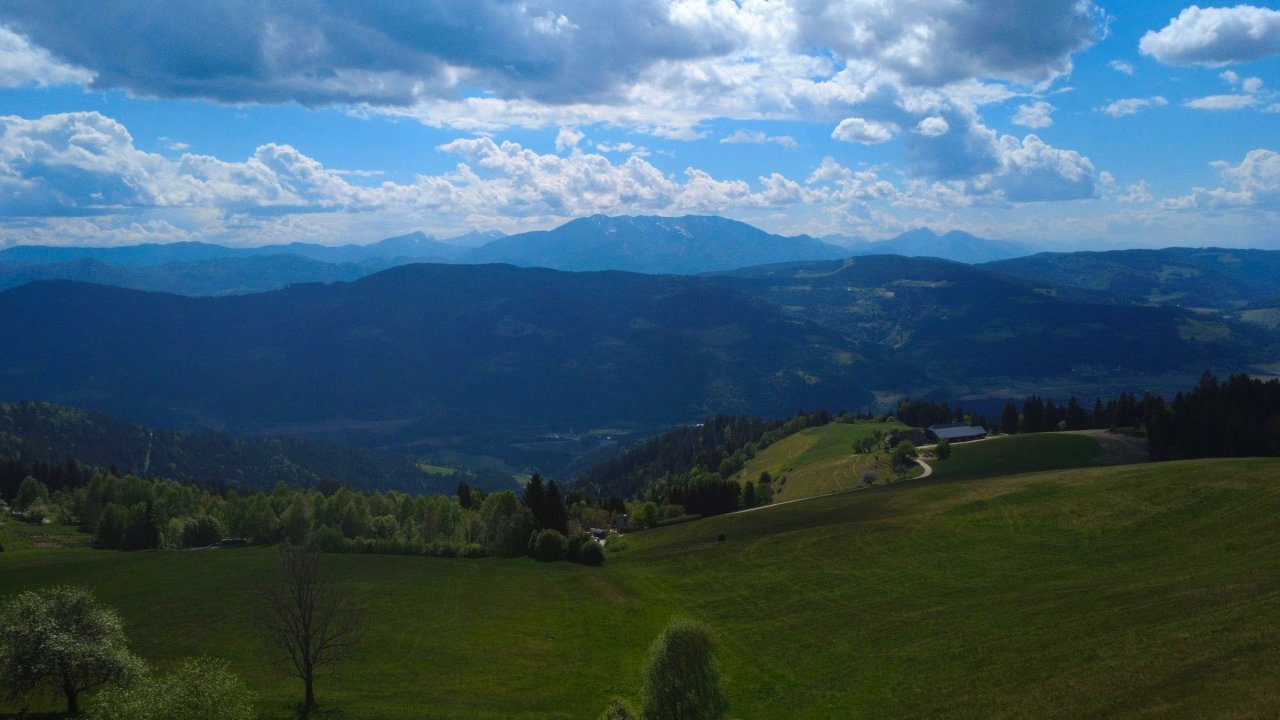 Pogled v dolino z Goriškega vrha čez Strojno, v ozadju pa so z Smrekovc, Raduha, Peca in dva vrhova Ojstrica (Obirja), vmes se v daljavi skriva gorenjski Storžič, če pa bi bilo sonce bolj proti jutru in nebo čistejše, pa se bi skrajno desno videl celo Triglav.